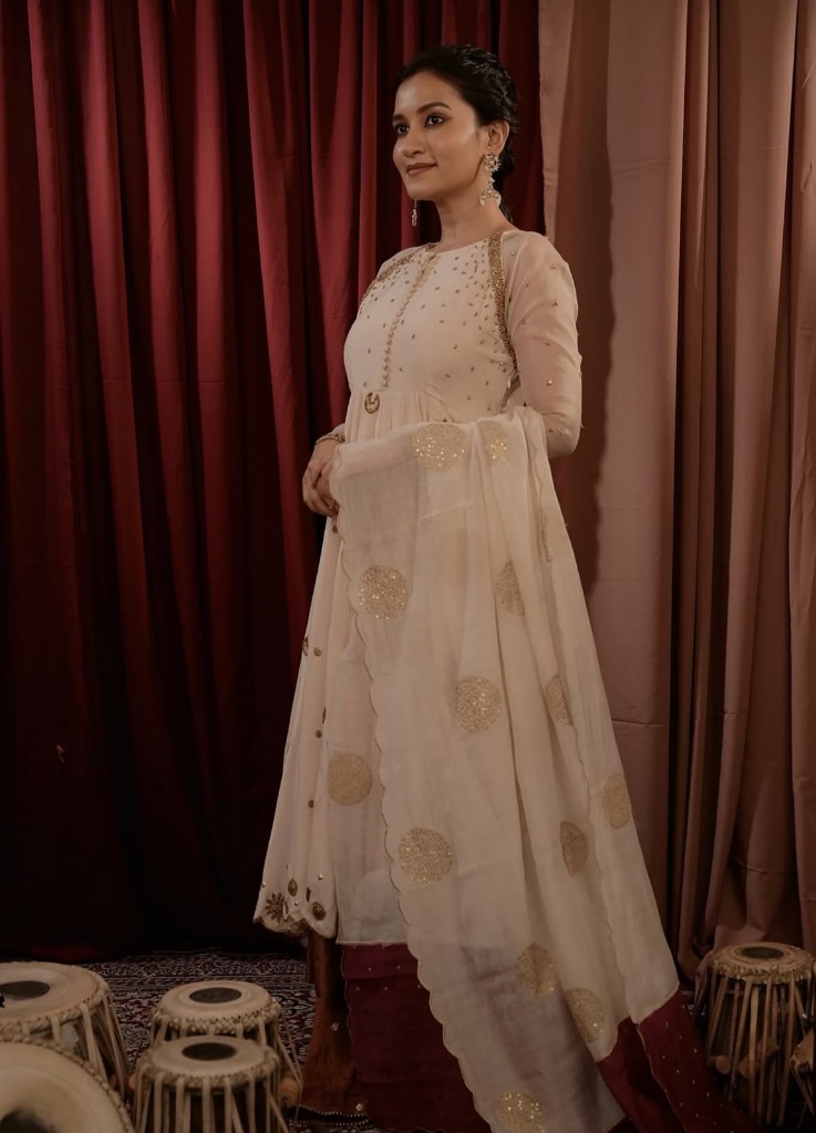 Portrait of a woman wearing an elegant, minimal ivory and champagne handloom Chanderi silk tunic with fine hand-finished details, showcasing investment dressing Indian fashion in a naturally lit space.